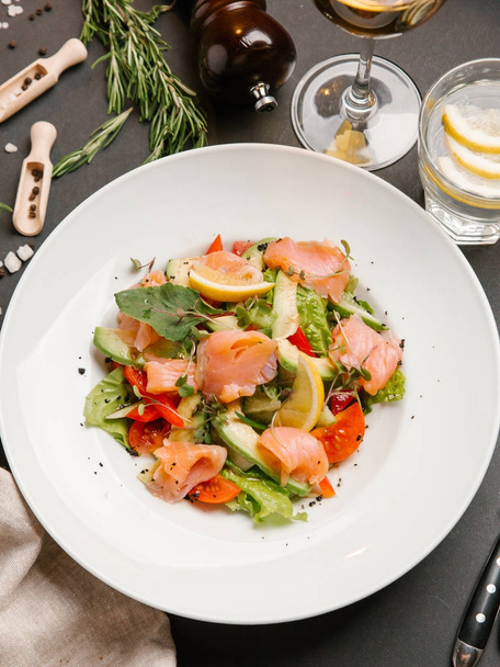 ensalada con salmón salado y verduras servidas en plato blanco
 - Foto, imagen