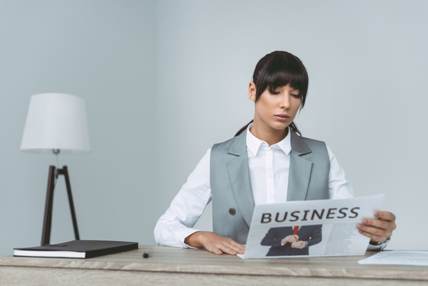 businesswoman reading newspaper in office on gray - 写真・画像