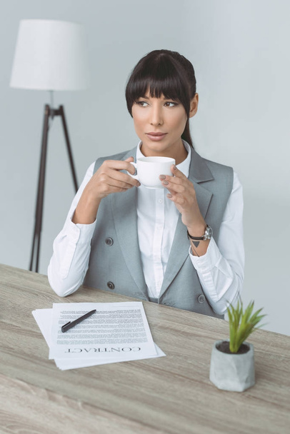 attractive businesswoman drinking coffee and looking away isolated on gray - Фото, изображение