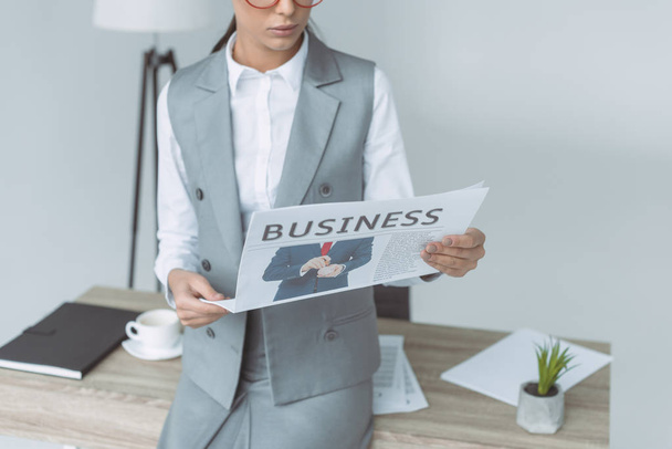 cropped image of businesswoman reading newspaper isolated on gray - Foto, imagen