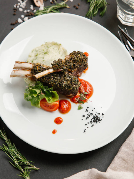 lamb chops under herbal sauce with mush potato served with tomato sauce on white plate - Photo, Image