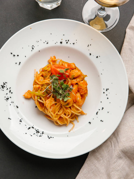  Spaghetti z krewetkami podawane z ziół i pomidor kawałek na białym talerzu - Zdjęcie, obraz