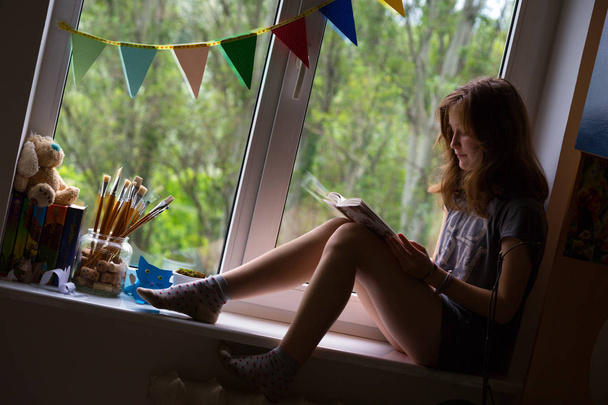 teen girl sitting on a windowsill  - Fotó, kép