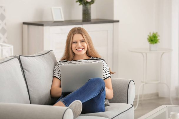 Beautiful woman using laptop while resting on sofa at home - Фото, изображение