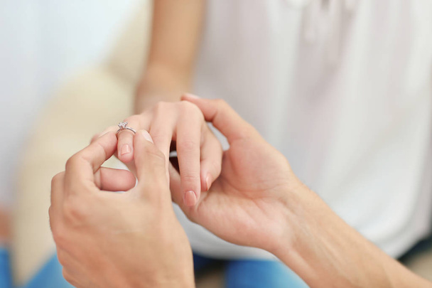Man putting engagement ring on fiancee's finger indoors - Zdjęcie, obraz