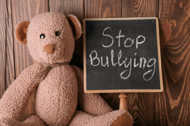 Chalkboard with text STOP BULLYING and toy on wooden background - Fotó, kép