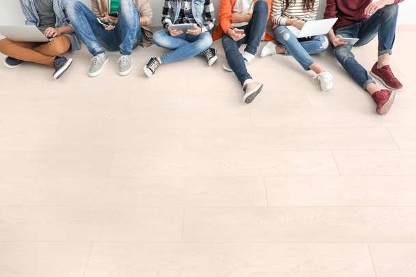 Group of teenagers with modern devices sitting on floor - Fotografie, Obrázek