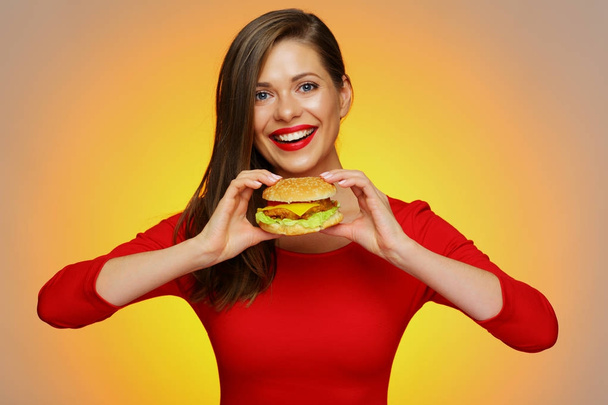 beautiful woman holding burger on yellow background  - Fotó, kép