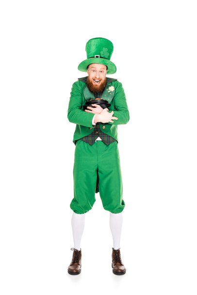 excited leprechaun in green suit holding pot of gold, isolated on white  - Foto, afbeelding