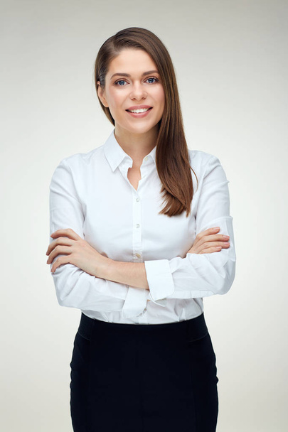 portrait of smiling businesswoman with long hair wearing white shirt standing with crossed arms on  light background  - Fotografie, Obrázek