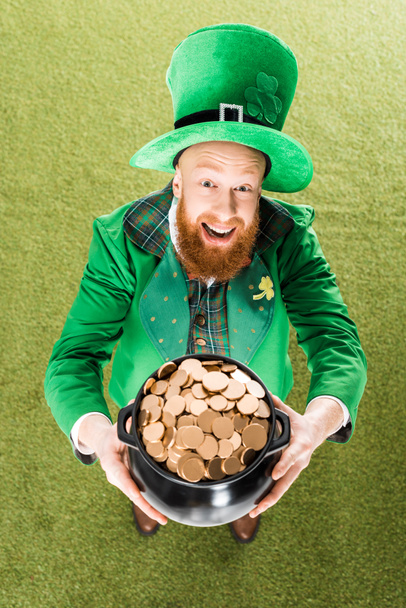 excited leprechaun holding pot of gold on green grass - Фото, изображение