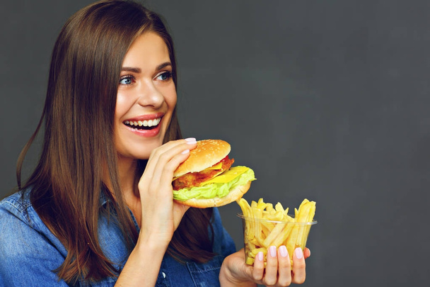 Smiling woman holding burger with potatoes fries - 写真・画像