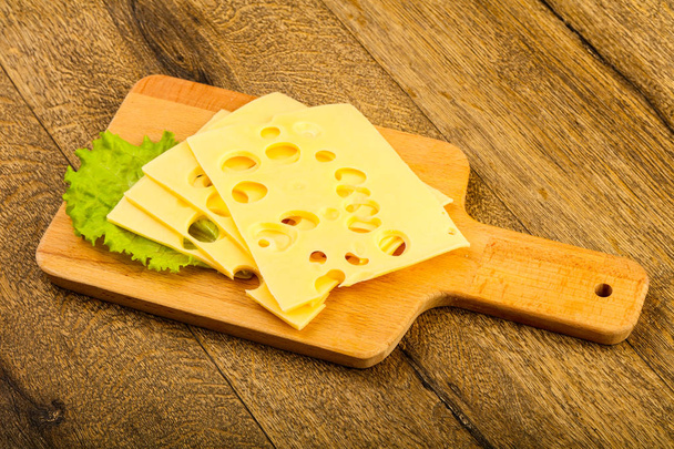 Scheibenkäse mit Salatblättern über dem hölzernen Hintergrund - Foto, Bild