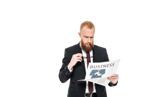 serious bearded businessman holding eyeglasses and reading newspaper isolated on white - Φωτογραφία, εικόνα