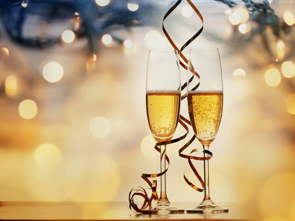 two champagne glasses with ribbons against holiday lights and fi - Фото, изображение