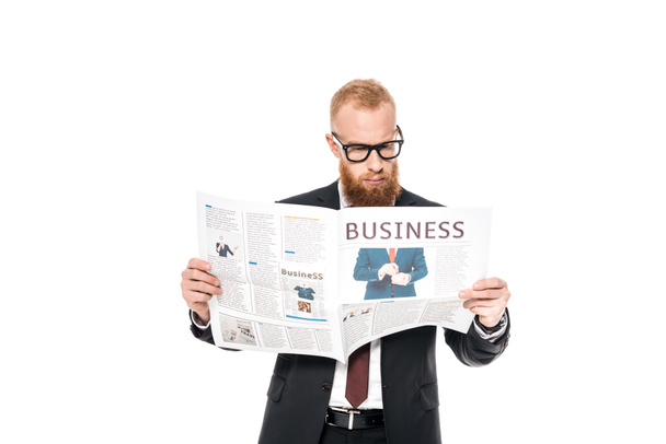 serious young bearded businessman in eyeglasses reading newspaper isolated on white  - 写真・画像