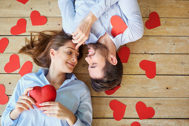 Couple lying on the wooden floor with hearts view from above. - Foto, afbeelding