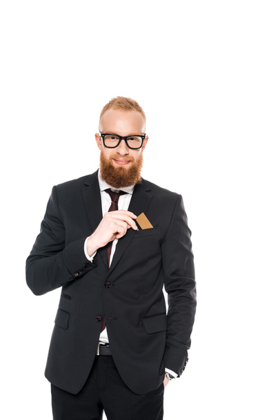 handsome bearded businessman in eyeglasses holding credit card and smiling at camera isolated on white  - Foto, imagen
