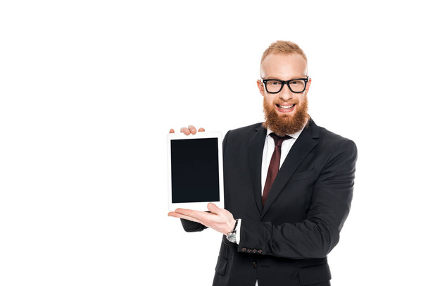 handsome bearded businessman holding digital tablet with blank screen and smiling at camera isolated on white - Photo, Image