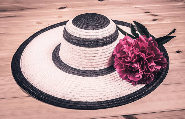 Hat and peony flower on wooden background. Vintage style - 写真・画像