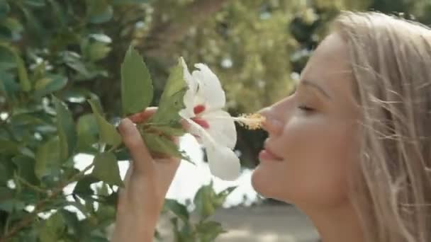 Young beautiful woman near blooming flower. Woman in spring blossom. Eco beauty and health concept. - Footage, Video