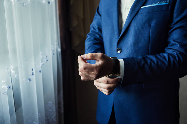 Επιχειρηματίας φοράει ένα σακάκι, αρσενικά χέρια closeup, γαμπρός ετοιμάζεται το πρωί πριν από την τελετή του γάμου - Φωτογραφία, εικόνα