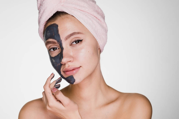 an attractive young girl with a pink towel on her head applied a clay useful mask to half the face - Photo, image