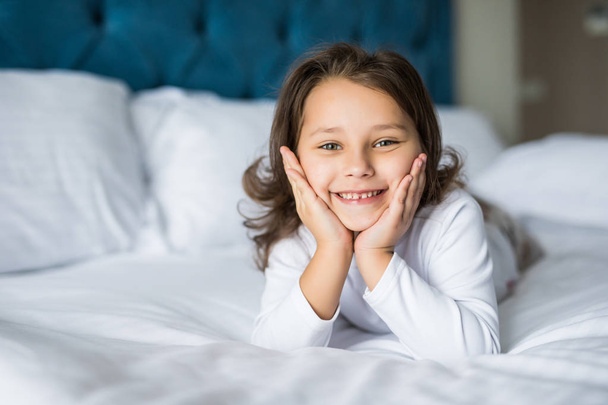 Adorable petite fille souriante avec sourire réveillée dans son lit
 - Photo, image