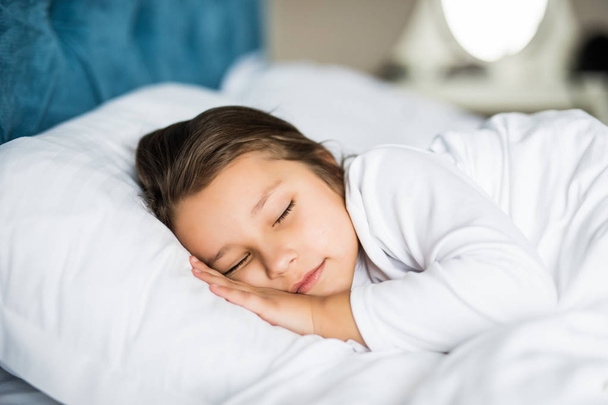 Bambina che dorme tranquillamente a letto nella sua luminosa stanza illuminata
 - Foto, immagini