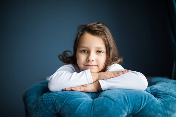 Malé mladé dítě sedí na židli ruce na tvář s krásou úsměv pohled na kameru v jejím pokoji doma - Fotografie, Obrázek