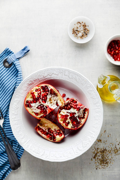 pomegranate with red seeds in a bowl on the kitchen table and fo - Foto, imagen