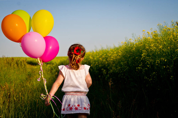 petite fille asiatique dans une robe de course à travers le champ de blé vert avec des ballons à la main, au ralenti
 - Photo, image