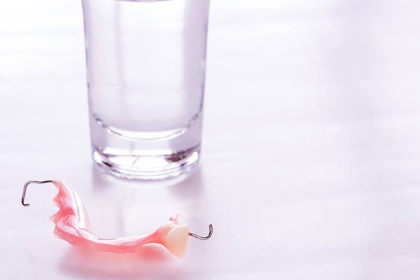 Close up acrylic dentures immersed in a glass of water - Photo, Image