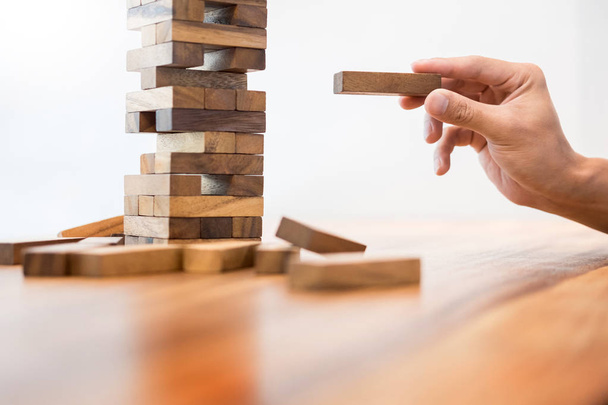 Plaatsen van houten blok op het concept van een toren van risico con zakenman - Foto, afbeelding