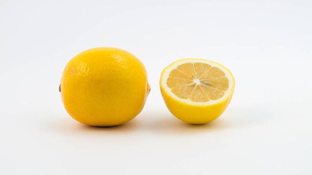 One whole lemon next to the cut half of the lemon. - Foto, Imagen