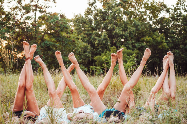 Sechs Mädchen liegen im Gras und heben die Beine - Foto, Bild