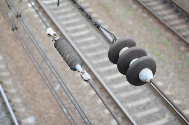 Isolatoren voor elektriciteit op de rijdraden op de achtergrond van een wazig spoorlijn bijhouden. Macro foto met selectieve aandacht - Foto, afbeelding