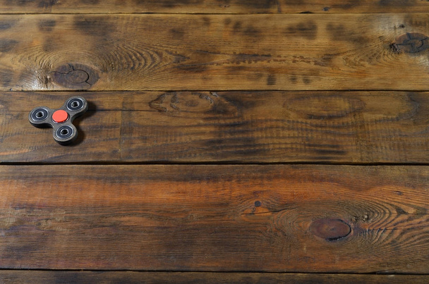 Ein seltener handgemachter hölzerner Fidget Spinner liegt auf einer braunen Holzoberfläche. Trendspielzeug zum Stressabbau - Foto, Bild