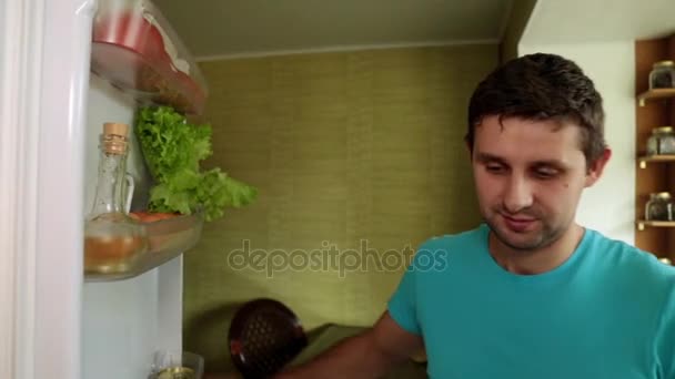 A man in the kitchen opens the refrigerator. The man takes out the fruit from the refrigerator. - Filmagem, Vídeo