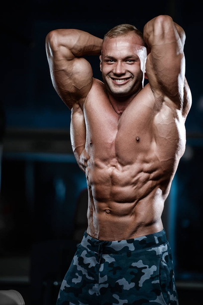 Brutal strong bodybuilder athletic men pumping up muscles with d - Foto, immagini