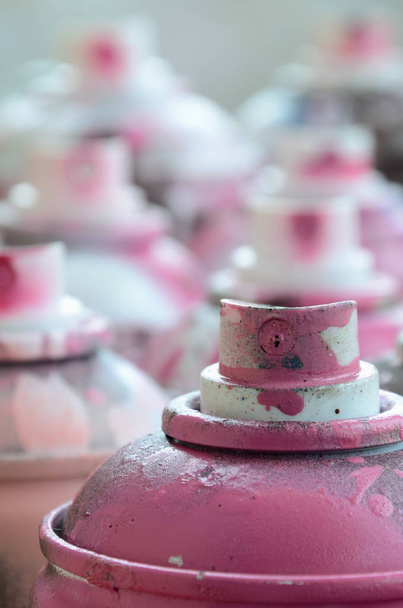 Una gran cantidad de latas de aerosol sucias y usadas de pintura rosa brillante. Fotografía macro con poca profundidad de campo. Enfoque selectivo en la boquilla de pulverización
 - Foto, Imagen
