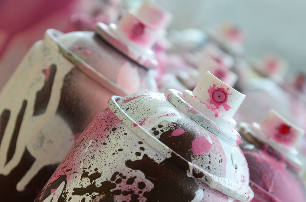 Um monte de latas de aerossol sujas e usadas de tinta rosa brilhante. Fotografia macro com profundidade de campo rasa. Foco seletivo no bico de pulverização
 - Foto, Imagem