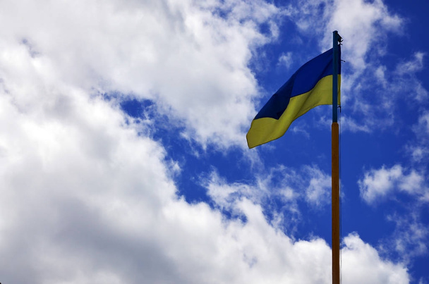 Ukrajinská vlajka proti modrá obloha s mraky. Oficiální vlajka ukrajinského státu zahrnuje žluté a modré barvy - Fotografie, Obrázek