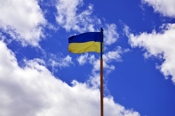 Vlag van de Oekraïense tegen de blauwe hemel met wolken. De officiële vlag van de Oekraïense staat bevat gele en blauwe kleuren - Foto, afbeelding
