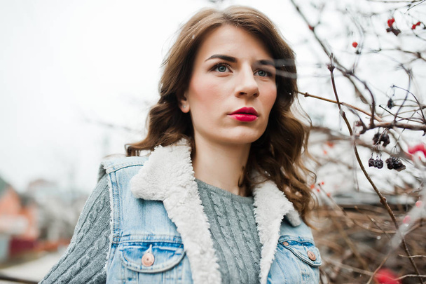 Portrait of brunette girl in jeans jacket at frozen bushes. - Fotó, kép