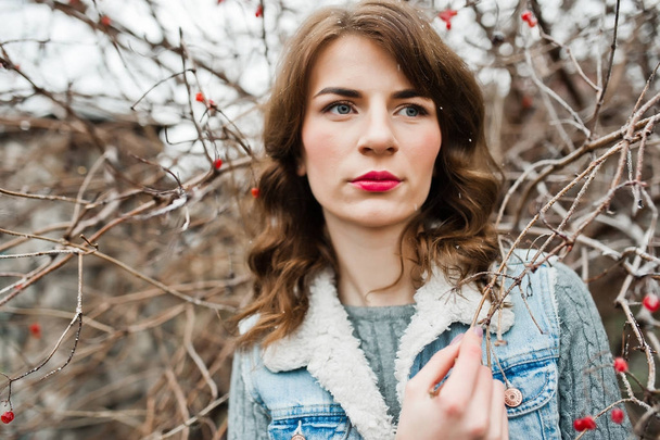 Portrait of brunette girl in jeans jacket at frozen bushes. - 写真・画像