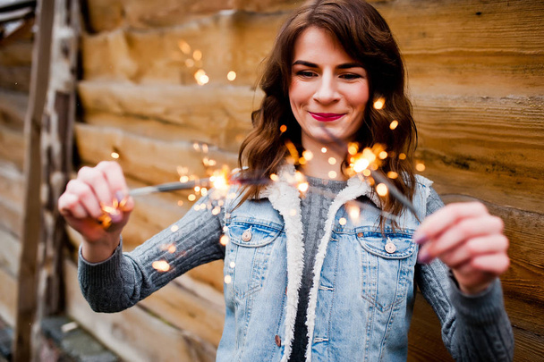 Portrait of brunette girl in jeans jacket with bengal lights in  - Photo, Image
