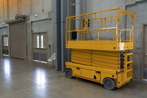 Plataforma de tesoura hidráulica amarela pronta para serviço e manutenção na área de trabalho da fábrica
. - Foto, Imagem