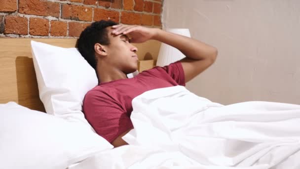 Fejfájás, stressz, az ágyban pihentető feszült afrikai férfi - Felvétel, videó