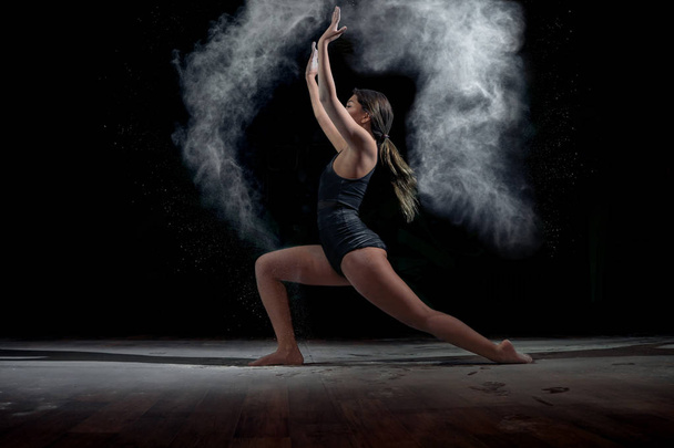 Dancing girl with flour on a black background - Foto, Imagen